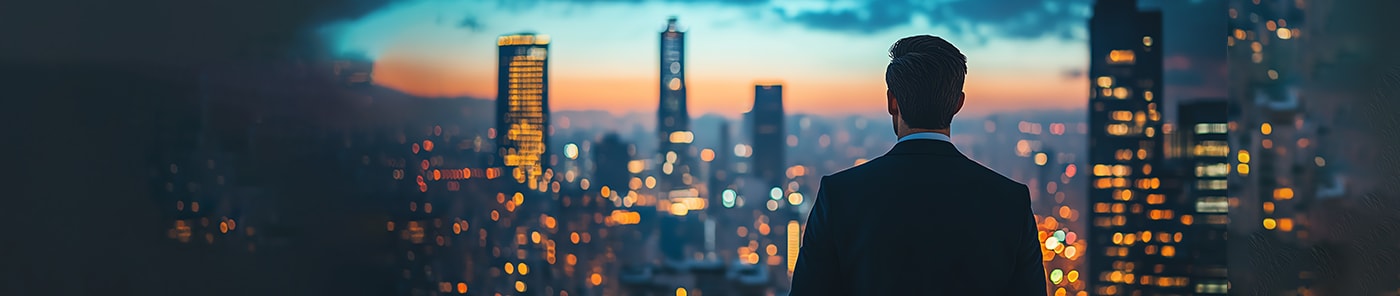 Businessman looking out over a city skyline at dusk