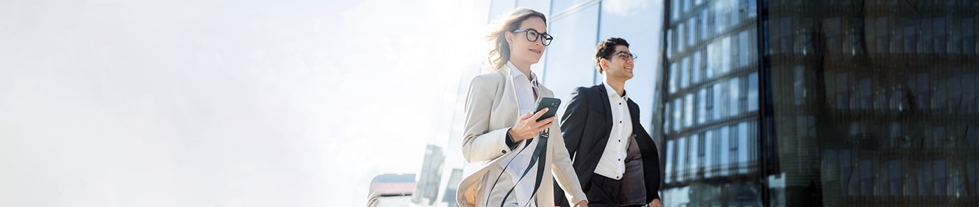 Two young managers walking and talking outside an office building