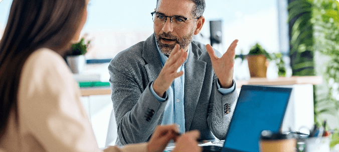 Assessor explaining a point to a colleague at a laptop