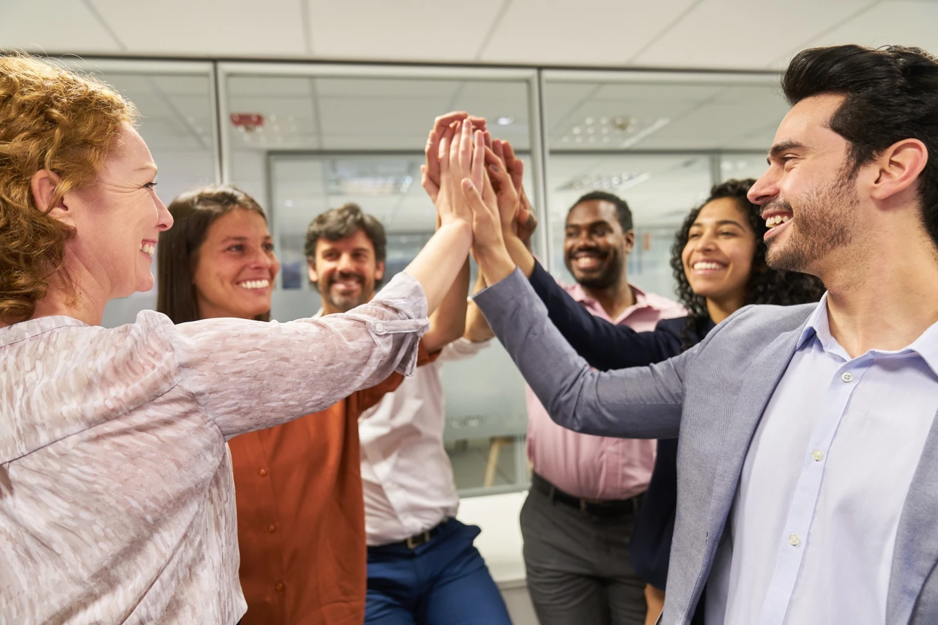 Smiling colleagues sharing a group high five in the office