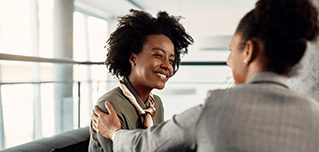 Mentor with a hand on a smiling colleague’s shoulder