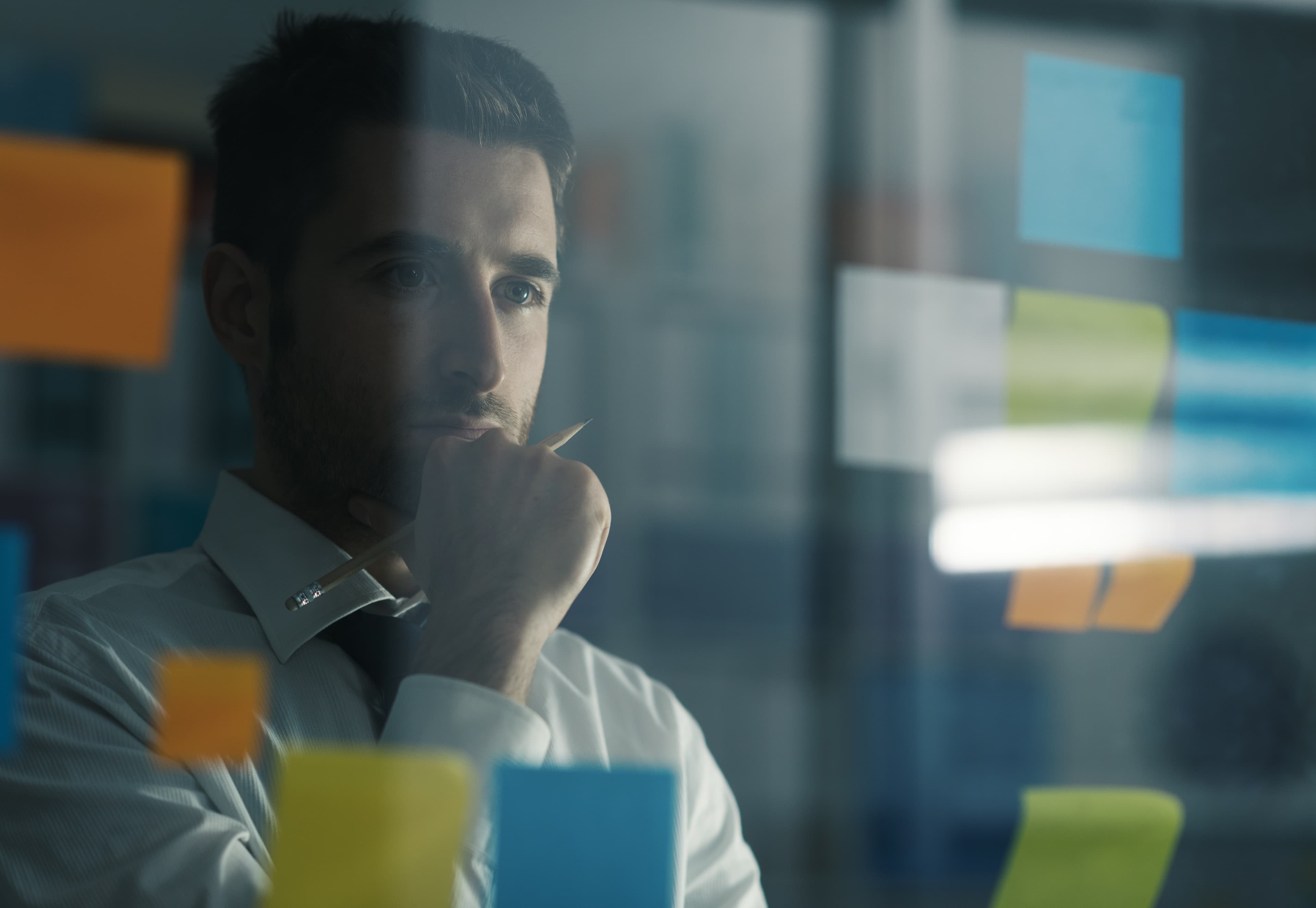 Professional deep in thought behind a glass wall of sticky notes