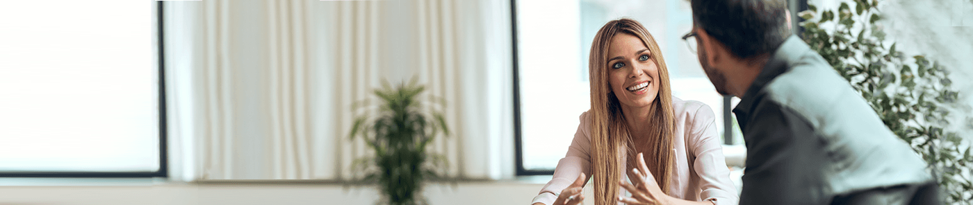 Young professional in conversation with a colleague at a desk